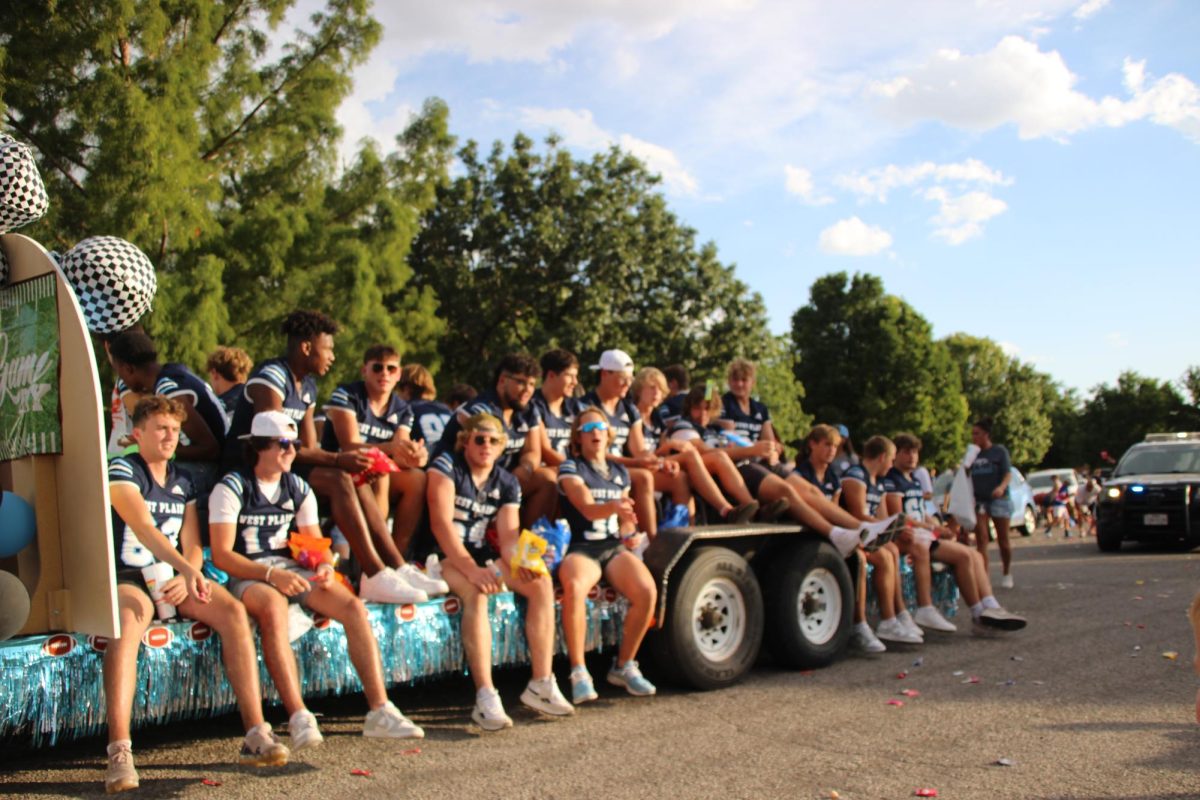 Riding on their float, varsity football players show school spirit and participate in the parade. 